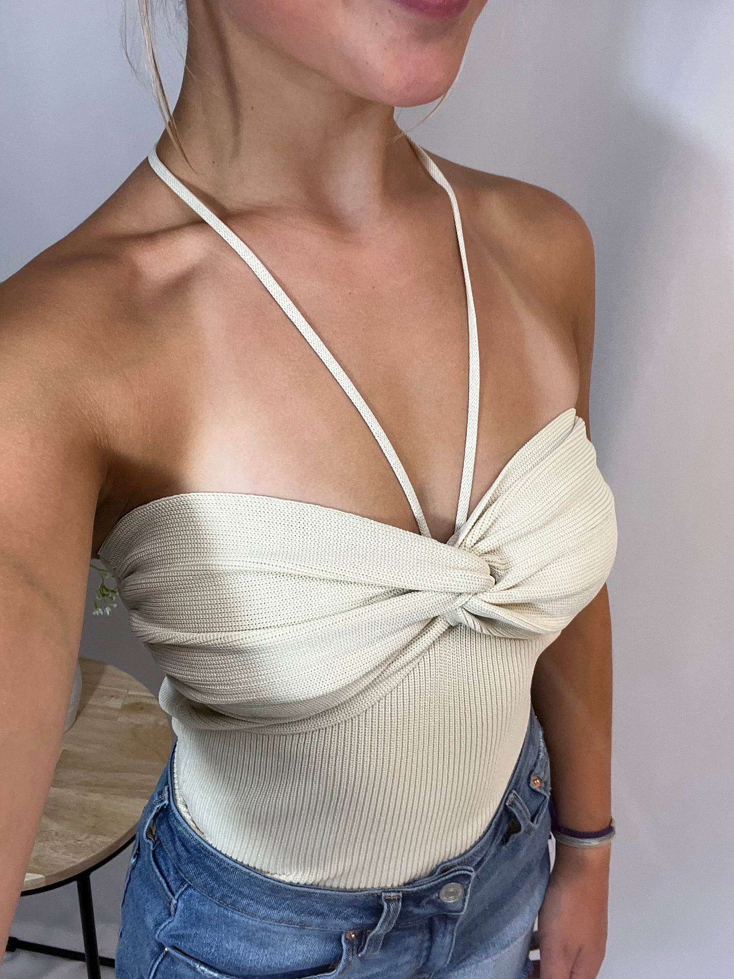 Close-up of cream knit convertible top with ruched bust and halter straps