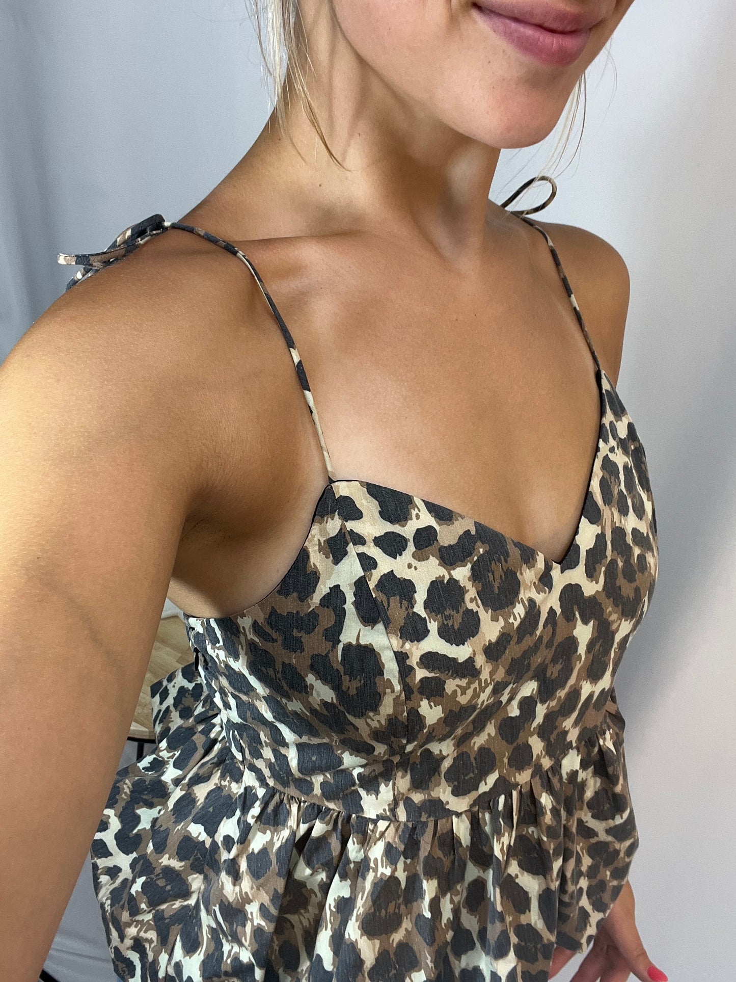 Close-up of cheetah print bubble hem top, women’s relaxed flowy blouse with playful hem pattern