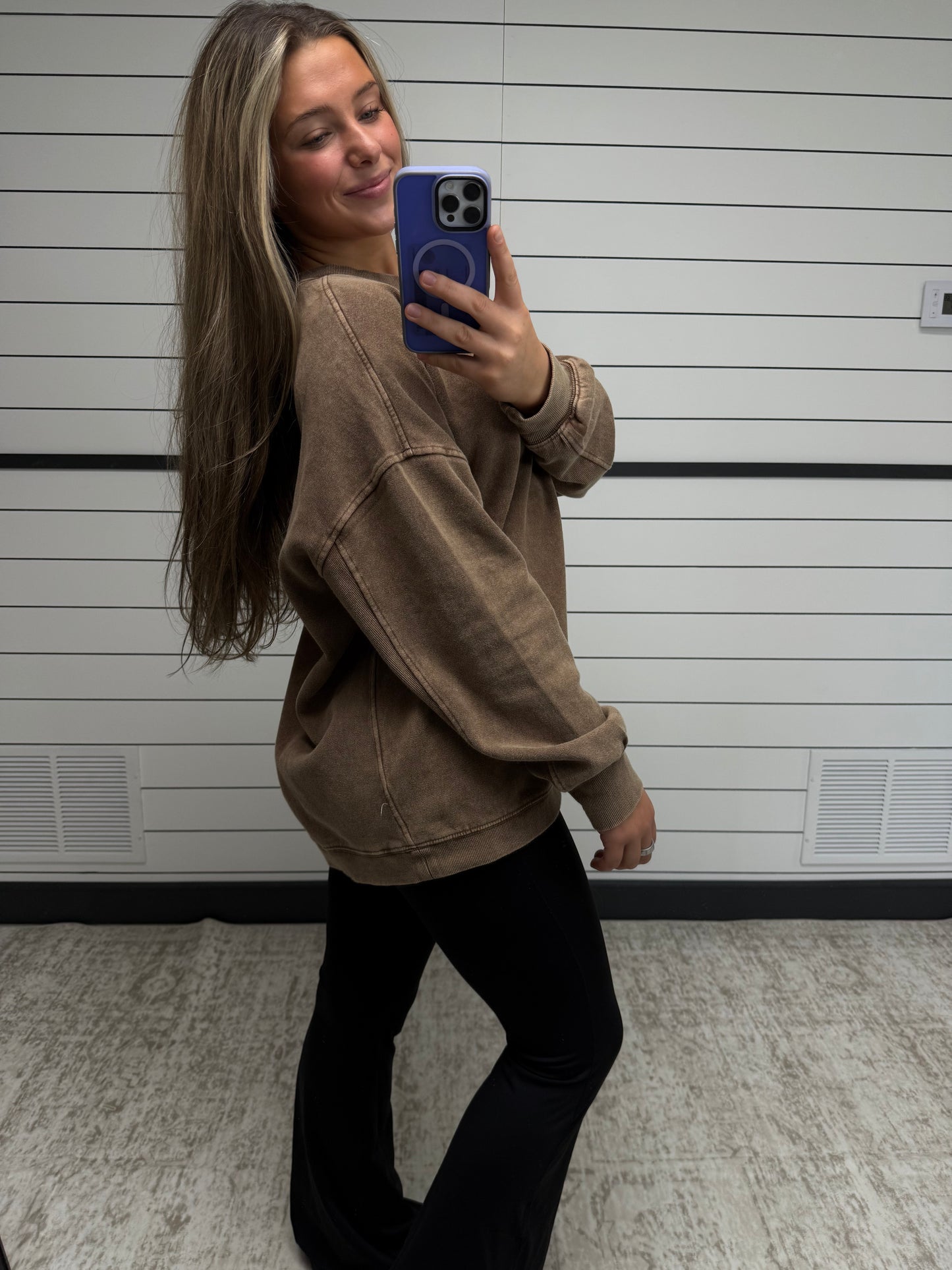 Person taking a mirror selfie wearing a brown jacket and black pants.