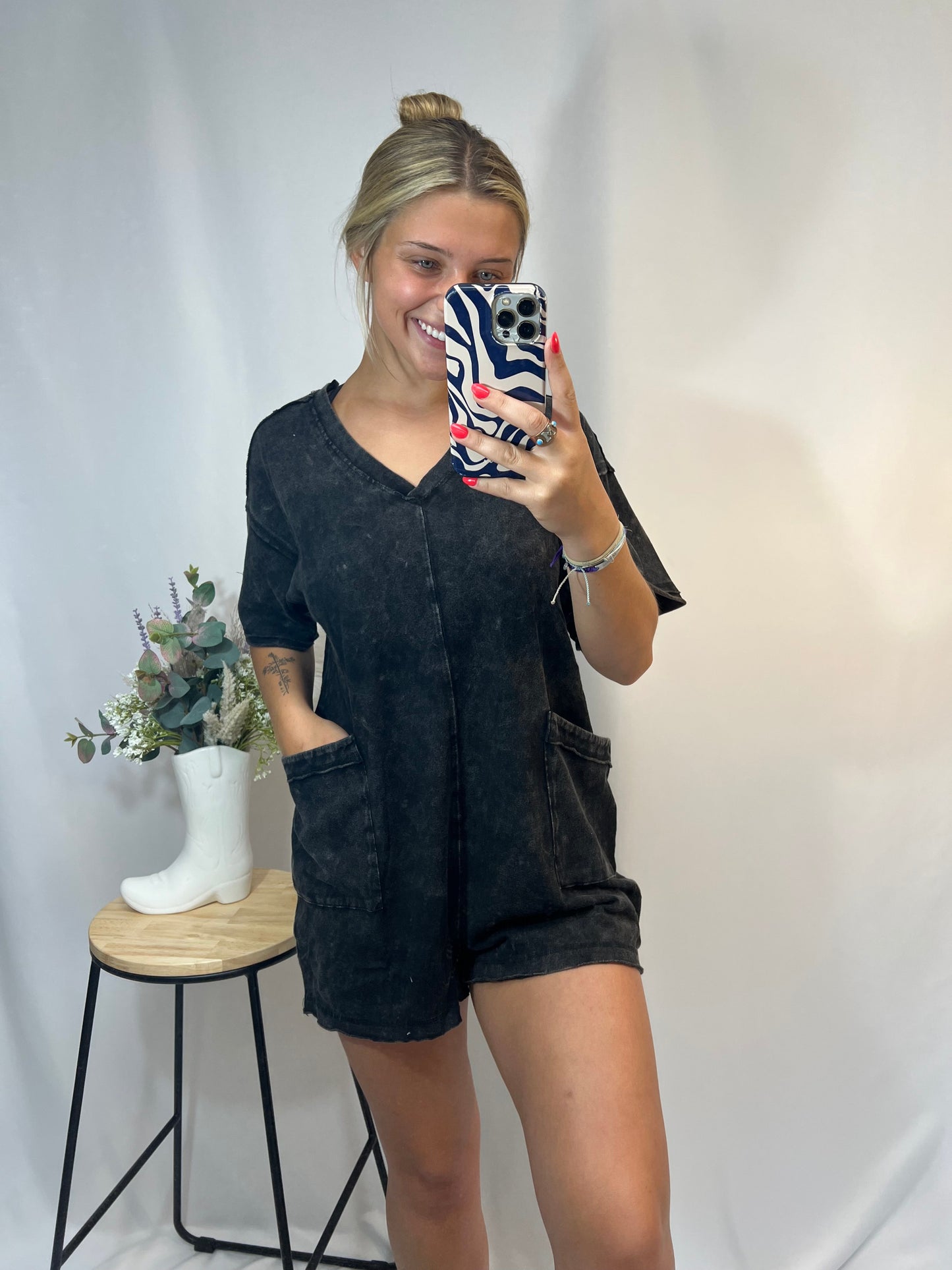 Young woman wearing black mineral wash romper with oversized fit and v-neckline