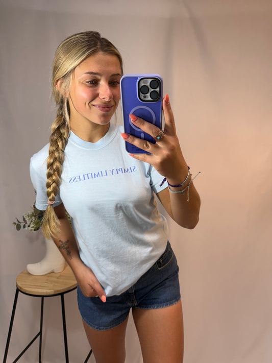 Person taking a mirror selfie wearing a white t-shirt and denim shorts.