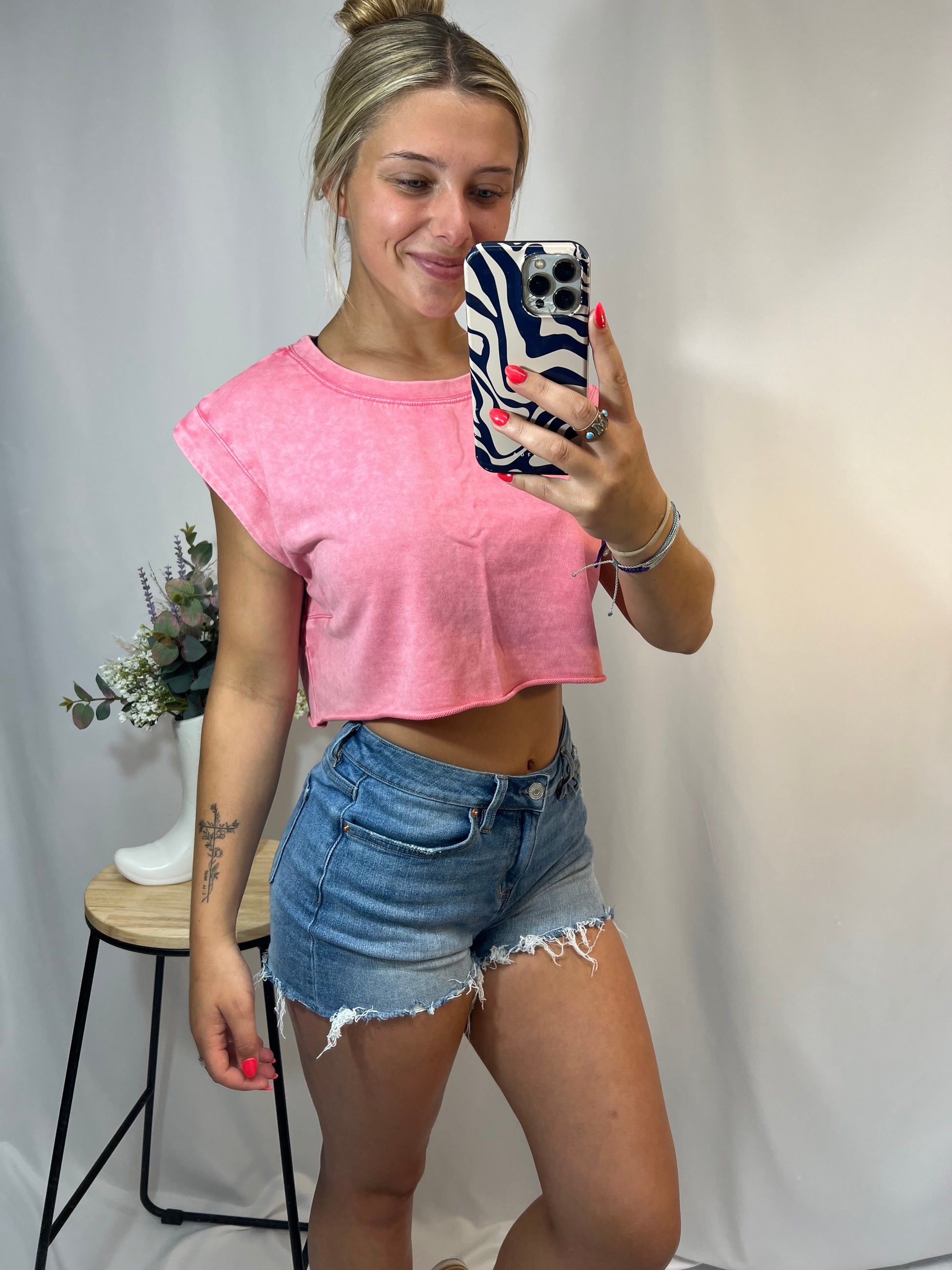 Close-up of pink cropped tank showing rolled sleeves and raw hem detail; perfect for casual summer outfits and trendy street style.