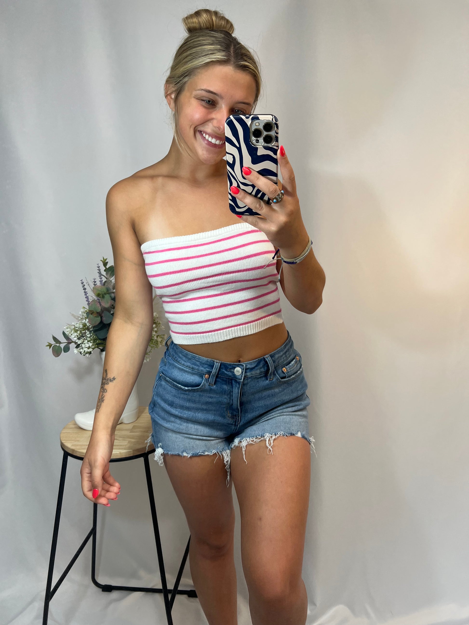 Woman wearing pink and white striped knit bandeau crop top with denim shorts