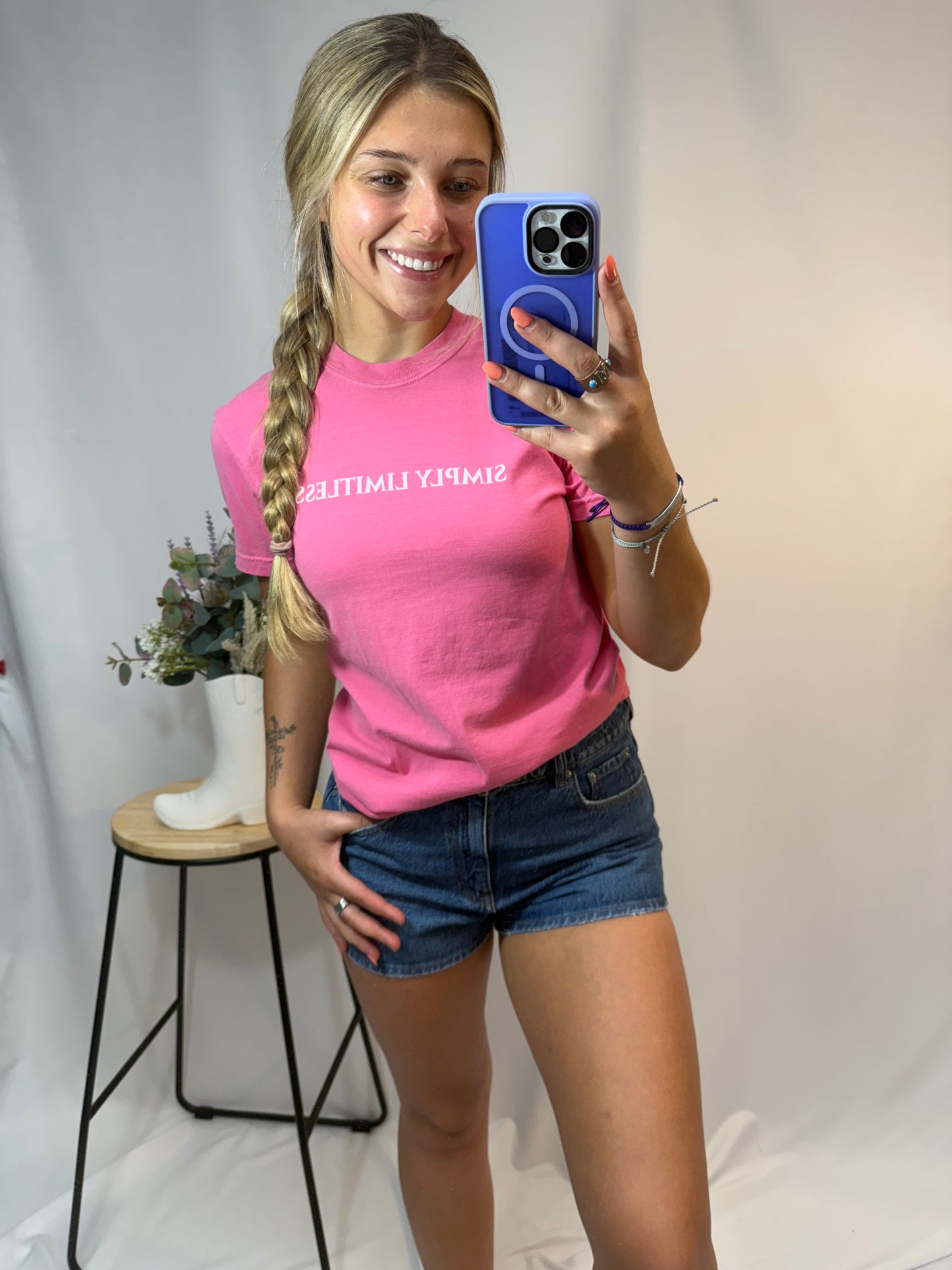 Person wearing a pink t-shirt with text, standing indoors.