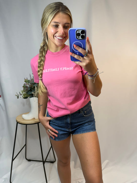 Person wearing a pink t-shirt with text, standing indoors.