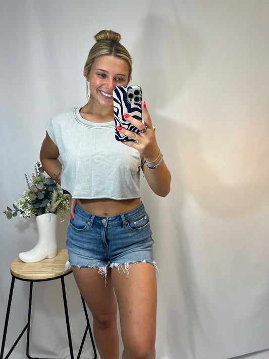 Girl modeling a light grey mineral wash cropped tank top with a boxy fit and rolled sleeves, styled with ripped denim shorts.

Young woman modeling high rise light wash cut off denim shorts with raw hem and frayed edges, styled with a cropped tee, casual cute outfit for summer