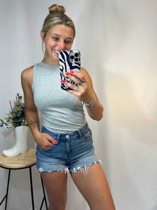 Woman wearing fitted high neck ribbed tank top in heather grey with denim shorts