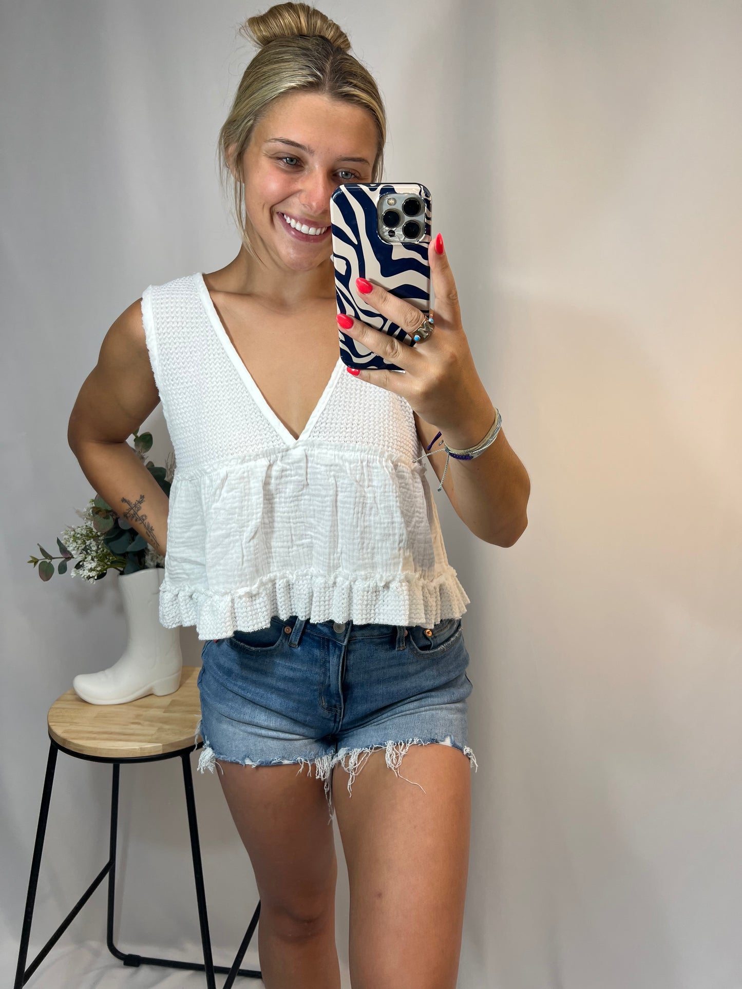 Woman modeling white ruffle cropped babydoll tank top with knit detailing