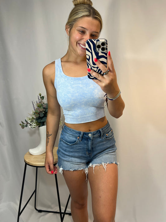 Woman wearing light blue ribbed cropped tank top with high-rise denim shorts
