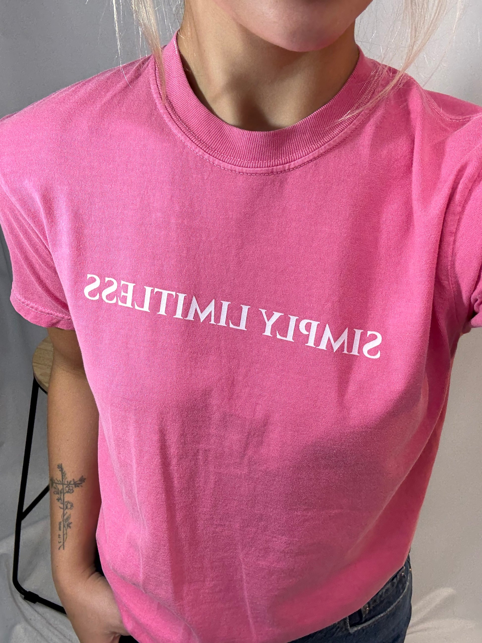 Person wearing a pink t-shirt with 'SIMPLY LIMITLESS' text.