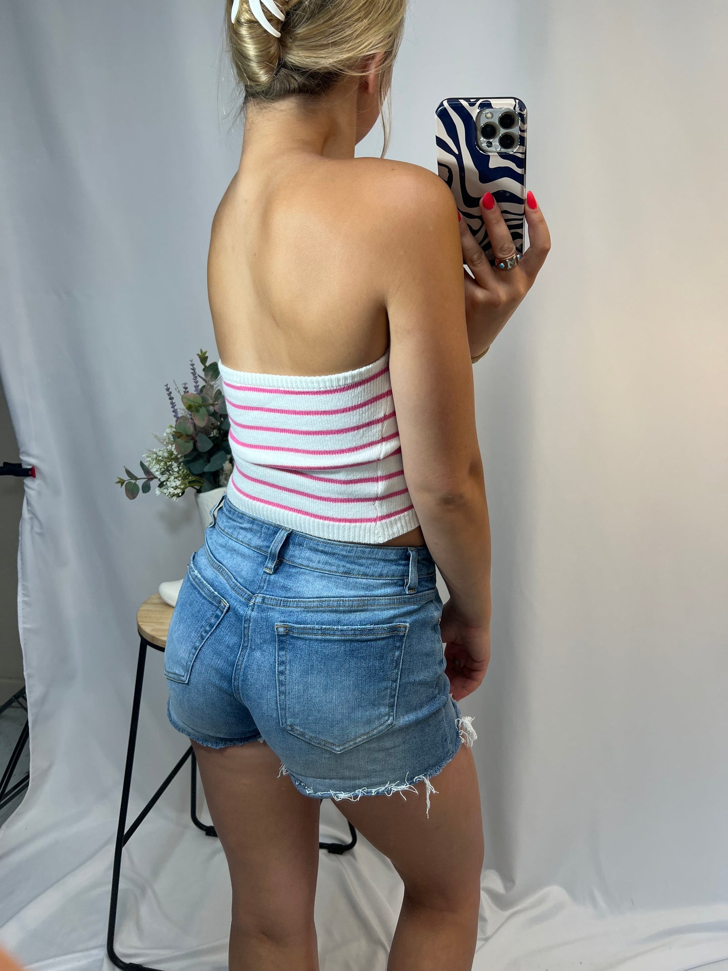 Back view of strapless pink stripe knit bandeau top paired with high-rise denim shorts
