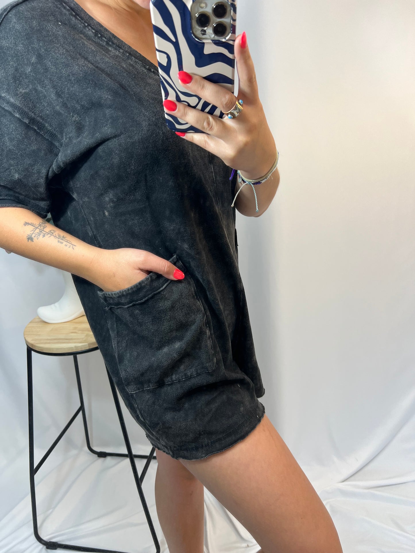 Close-up of black mineral wash romper with front pockets and raw-edge hem