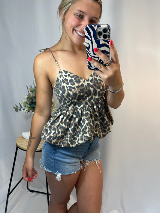 Woman wearing cheetah print bubble hem top with tie straps and denim shorts