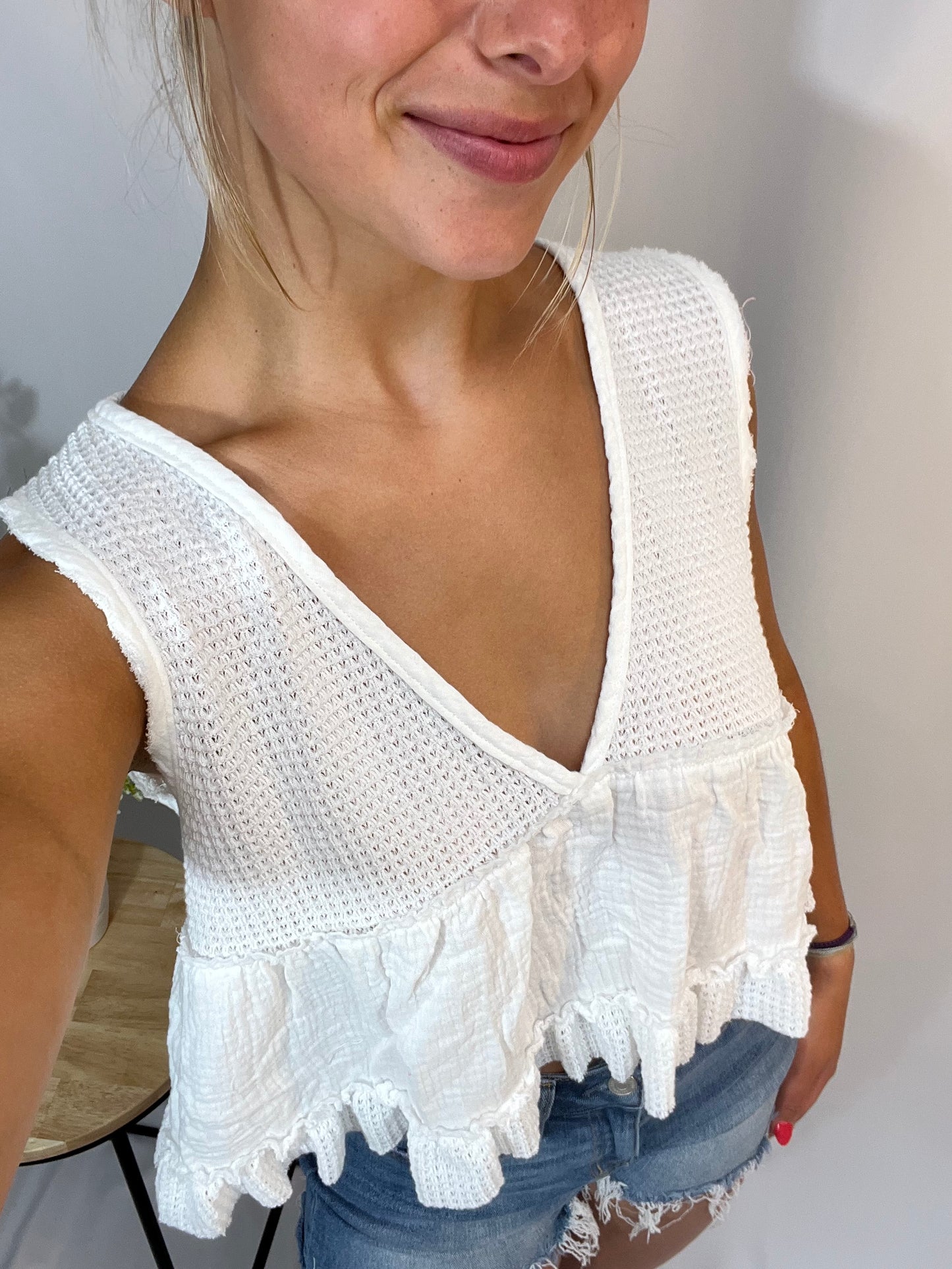 Close-up of white cropped tank with cotton gauze bottom and v-neck front