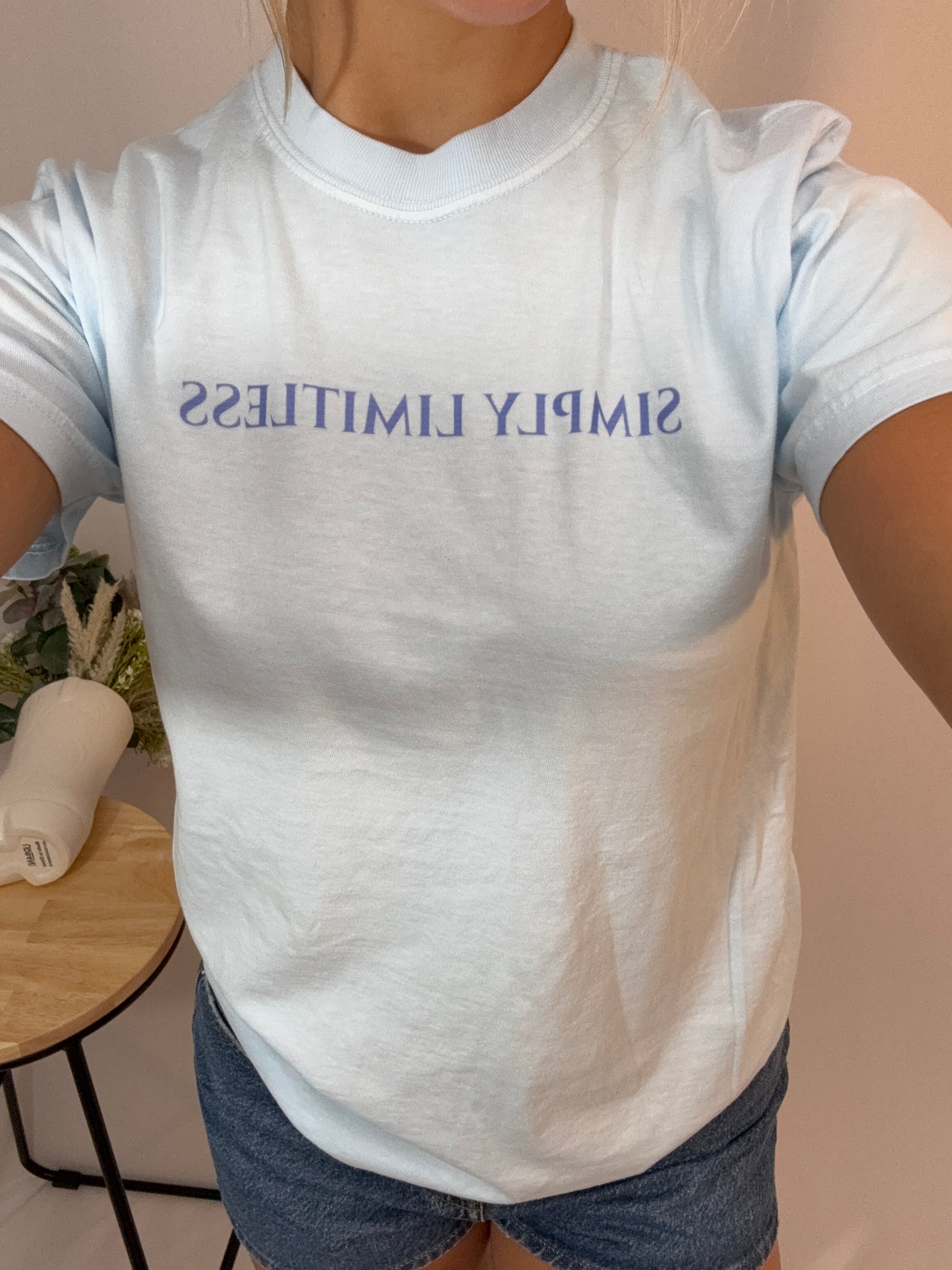 Person wearing a white t-shirt with 'SIMPLY LIMITLESS' text in blue.