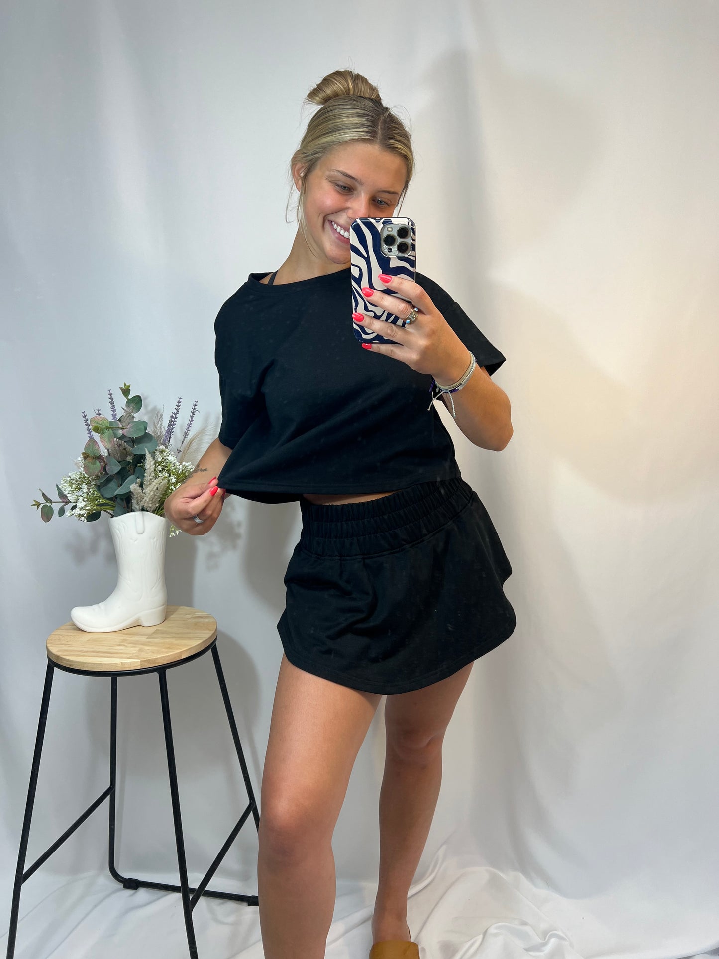 Woman modeling black cropped t-shirt and matching ruffle skort set