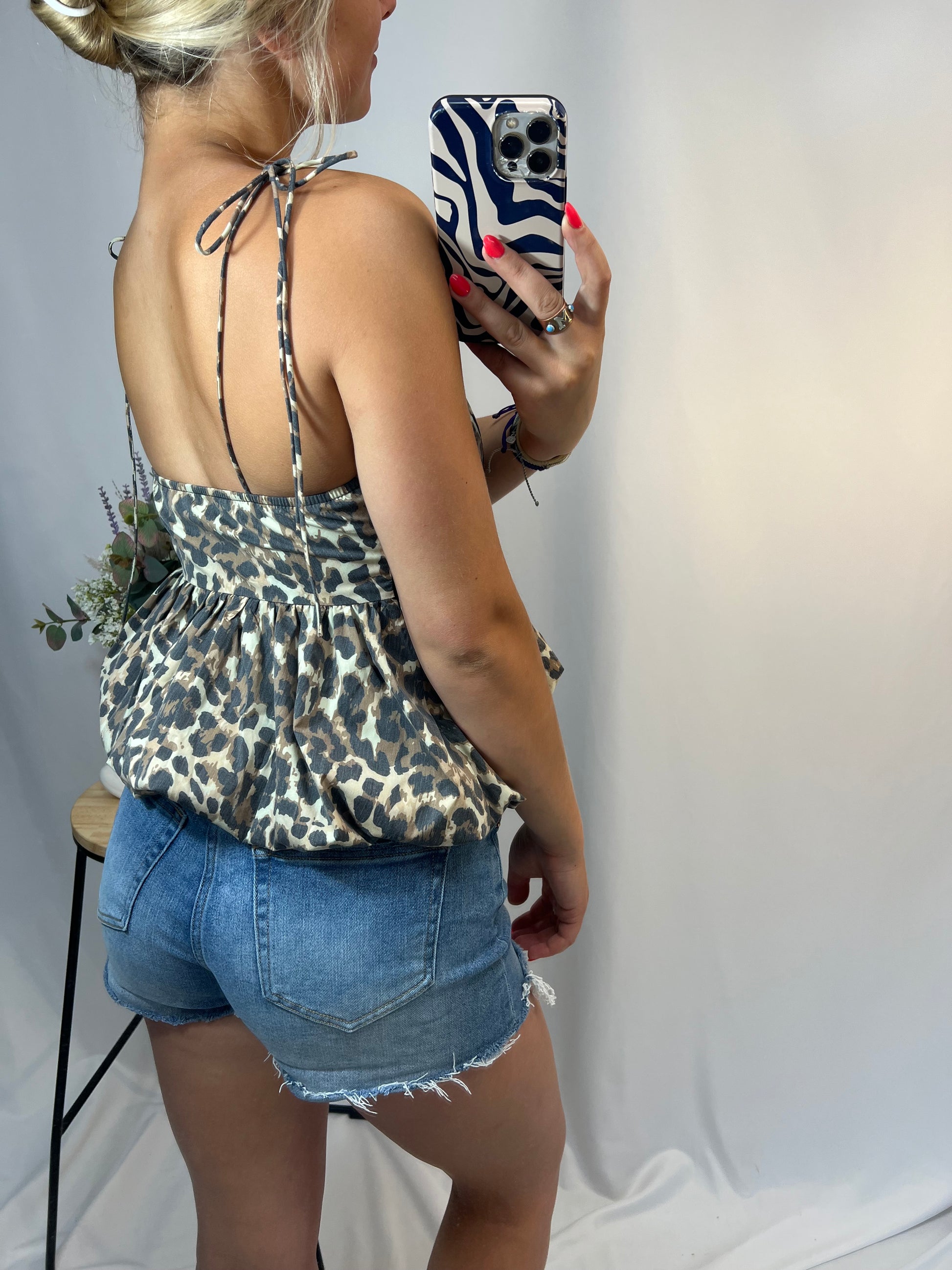 Back view of cheetah peplum top with adjustable tie straps and flowy hem