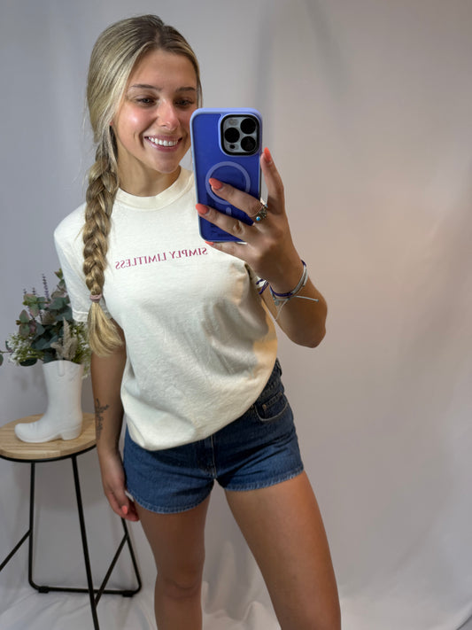 Person taking a mirror selfie wearing a white t-shirt and blue shorts.