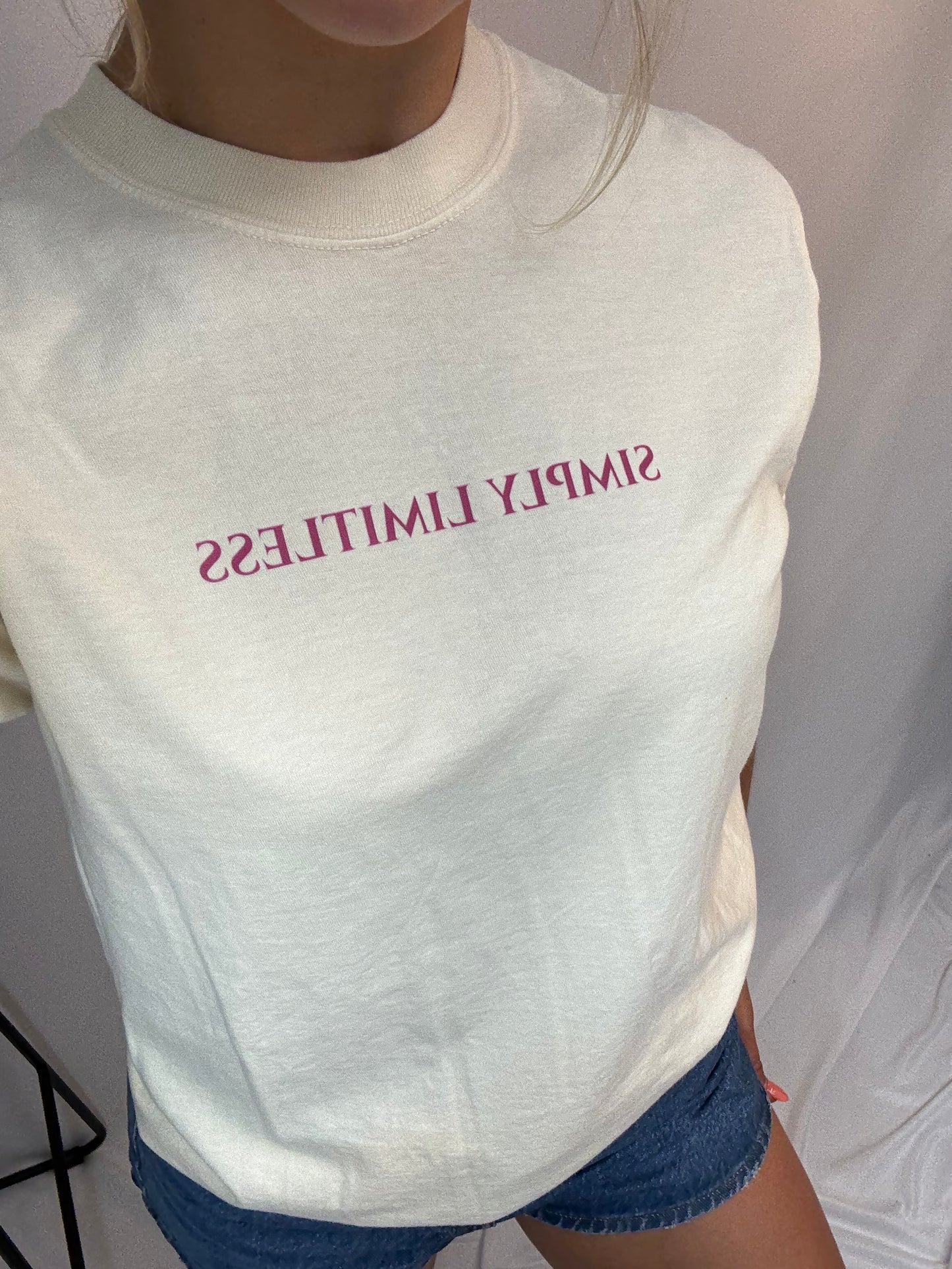 White t-shirt with 'SIMPLY LIMITLESS' text worn by a person.