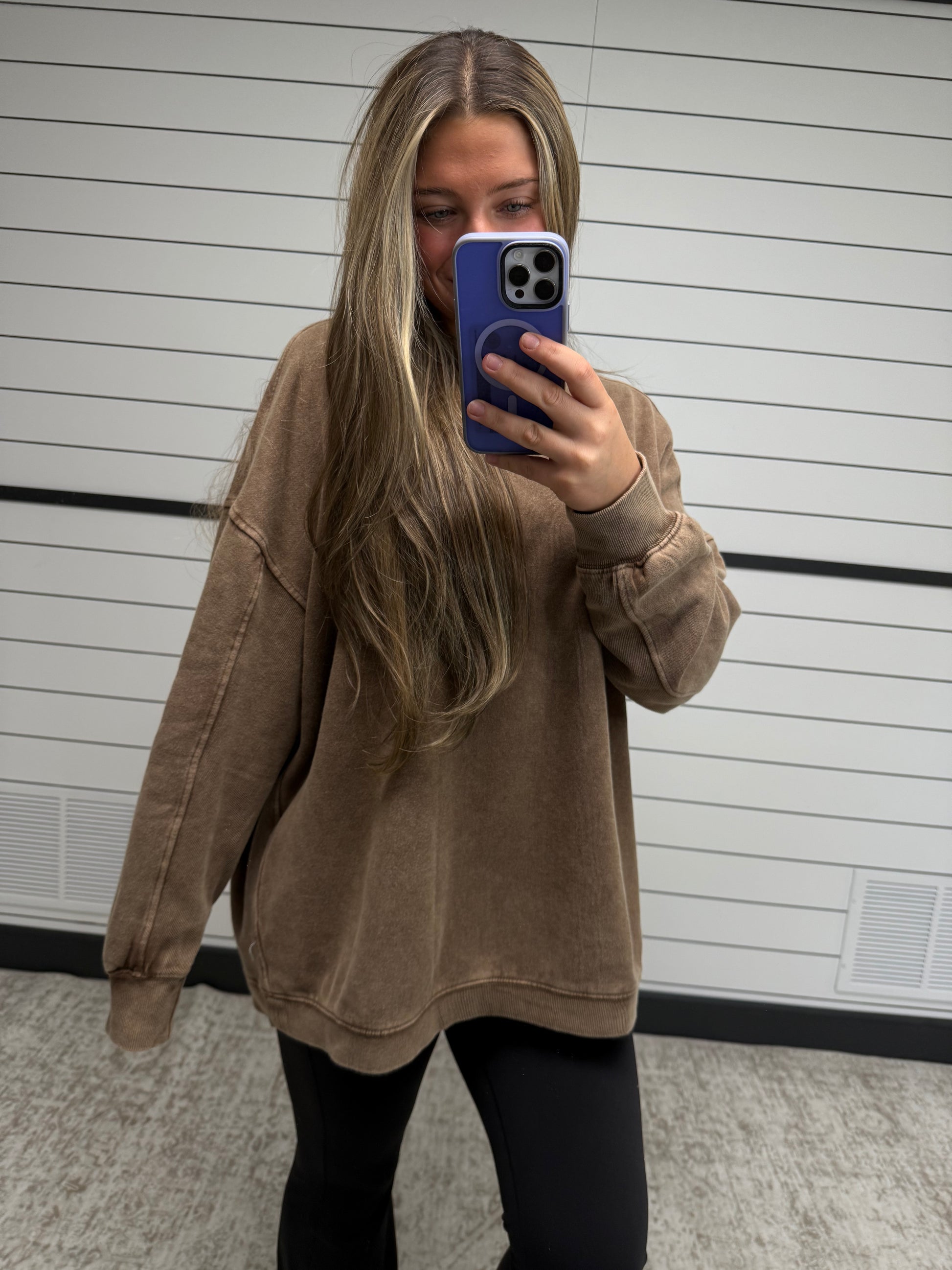 Person wearing a brown jacket taking a mirror selfie.
