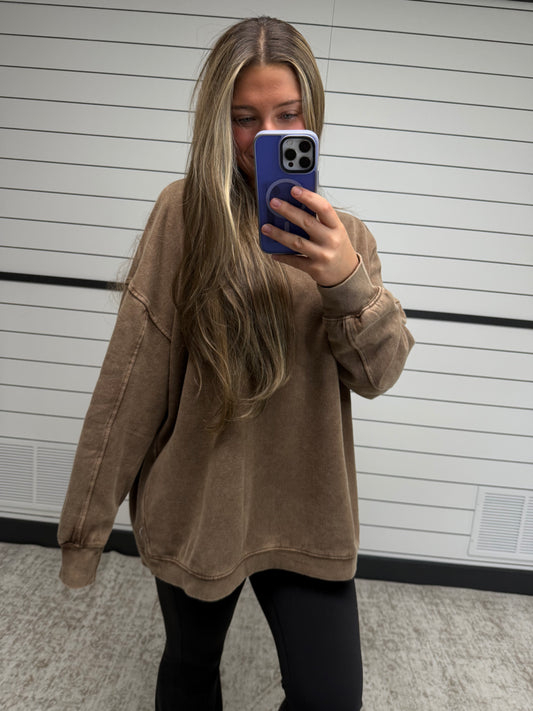 Person wearing a brown jacket taking a mirror selfie.