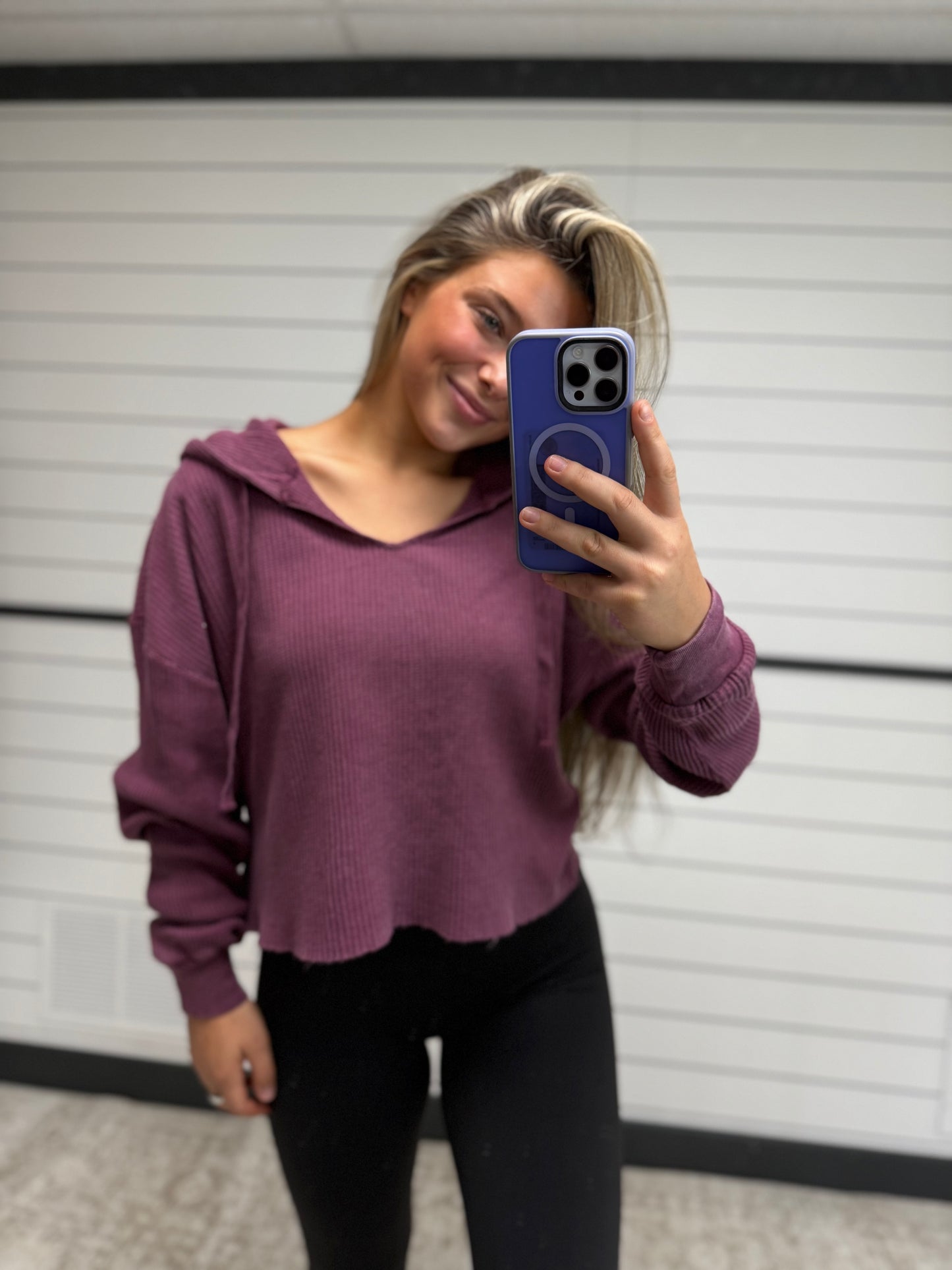 Person wearing a purple hoodie taking a mirror selfie.