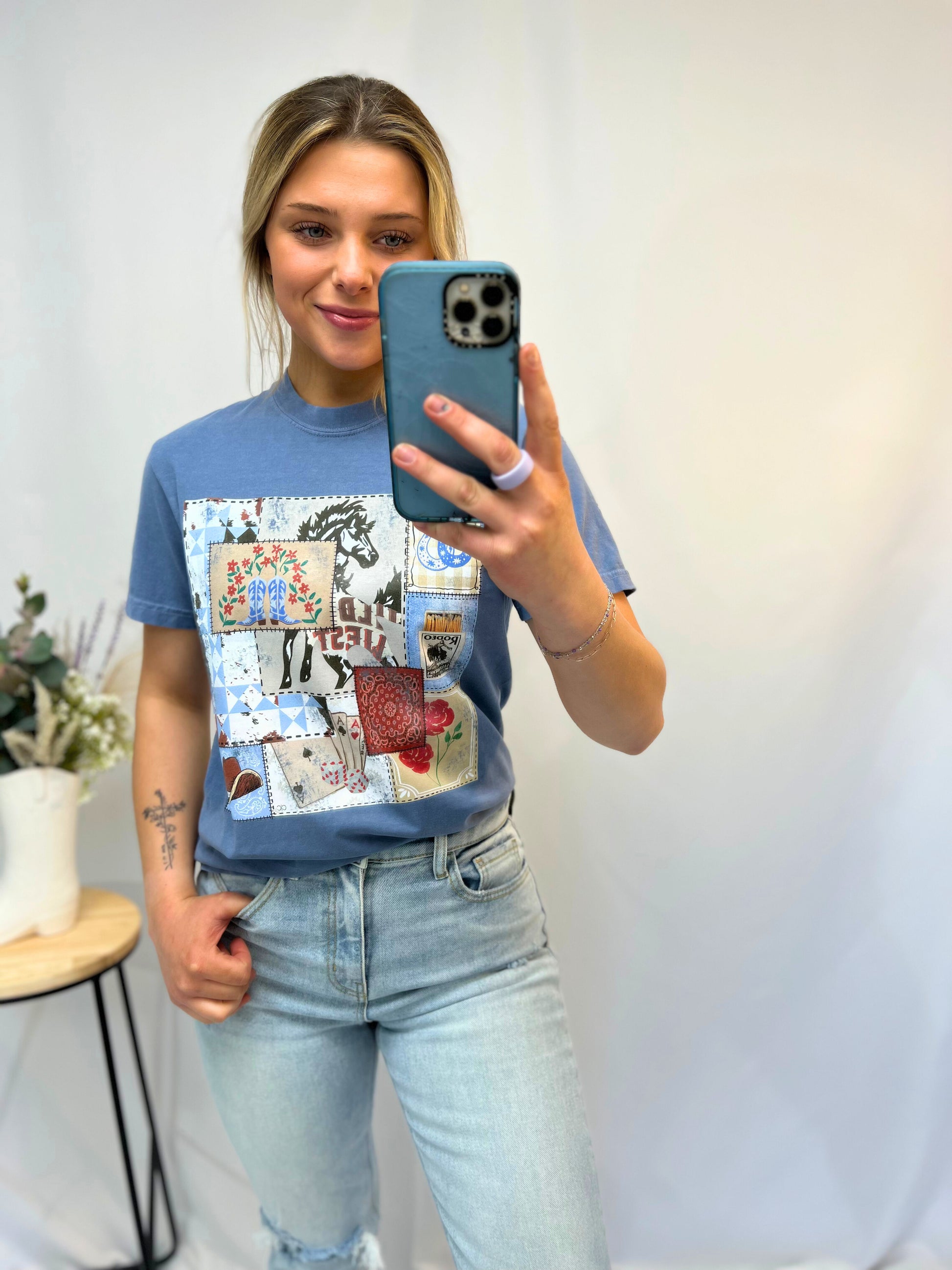 Full-body image of model styling the stone blue western rodeo graphic tee tucked into frayed denim shorts — rustic western outfit idea.