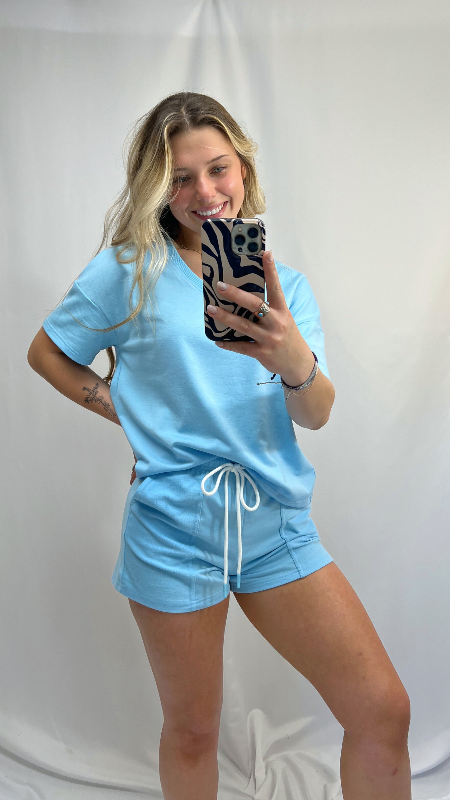 Young woman wearing sky blue v-neck matching set with drawstring shorts and relaxed t-shirt