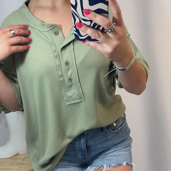 Model styling sage green oversized Henley shirt for girls — soft waffle knit casual tee with raw edge details