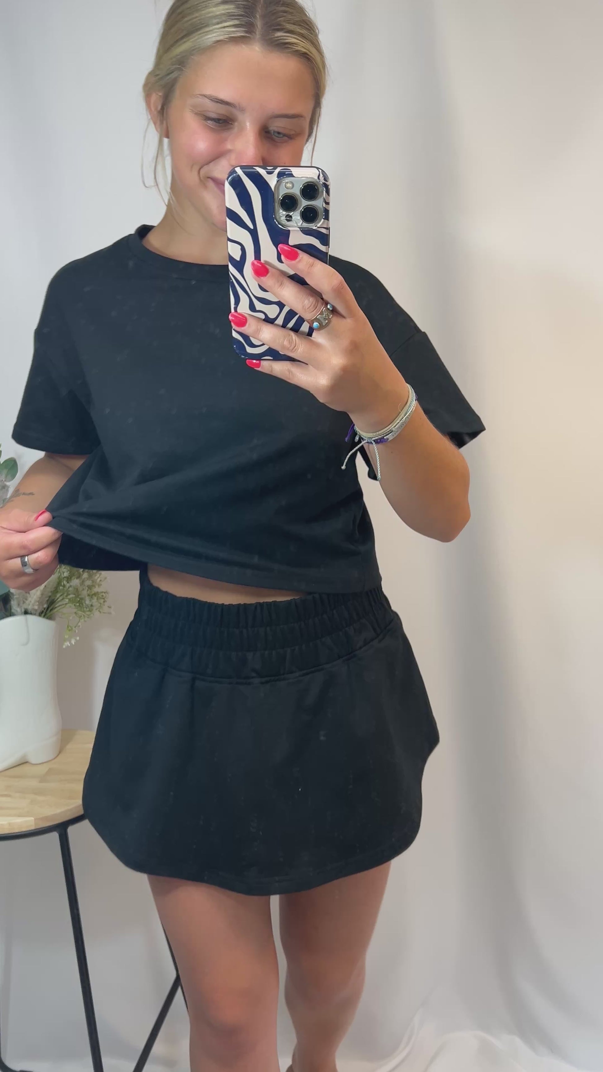 Woman modeling black cropped t-shirt and matching ruffle skort set