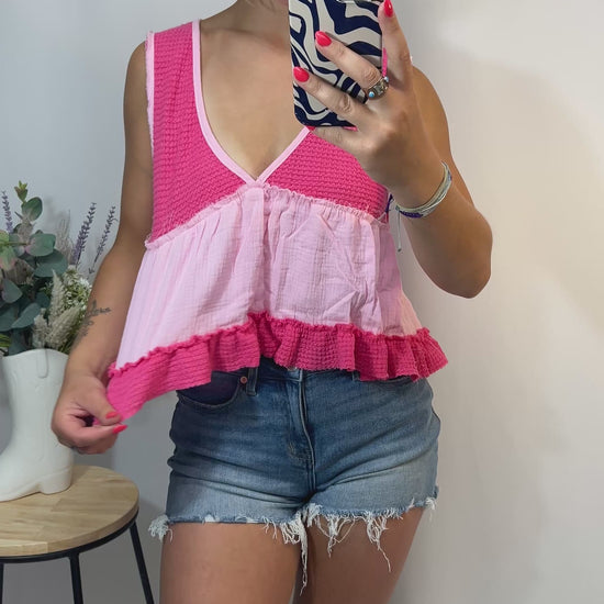 Playful styling of pink babydoll tank top paired with denim shorts, model smiling and posing