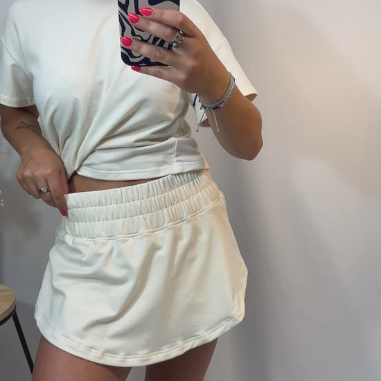 Woman wearing ivory cropped tee and matching high-waist skort with elastic waistband