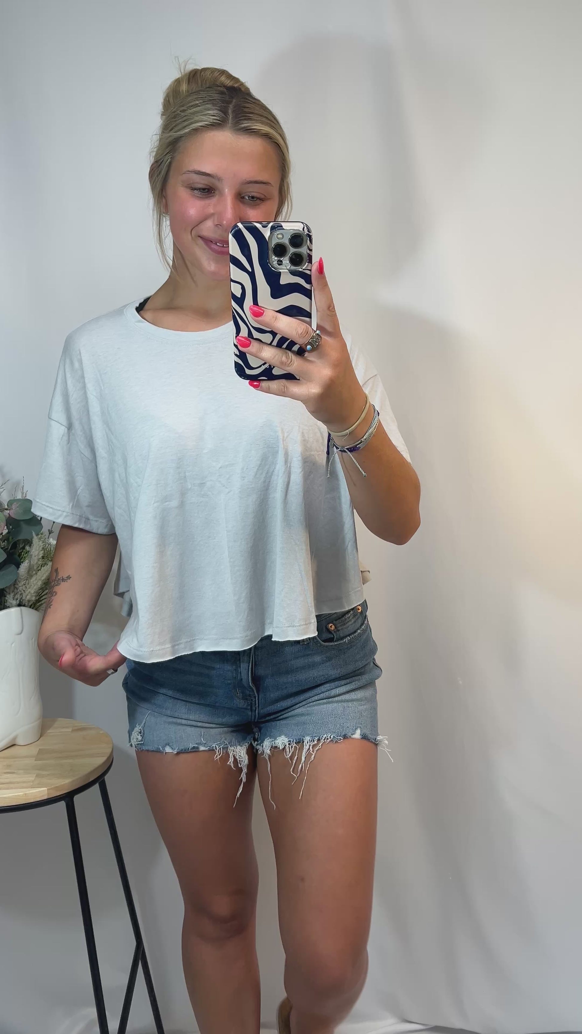 Young woman wearing heather grey oversized tee with distressed denim shorts