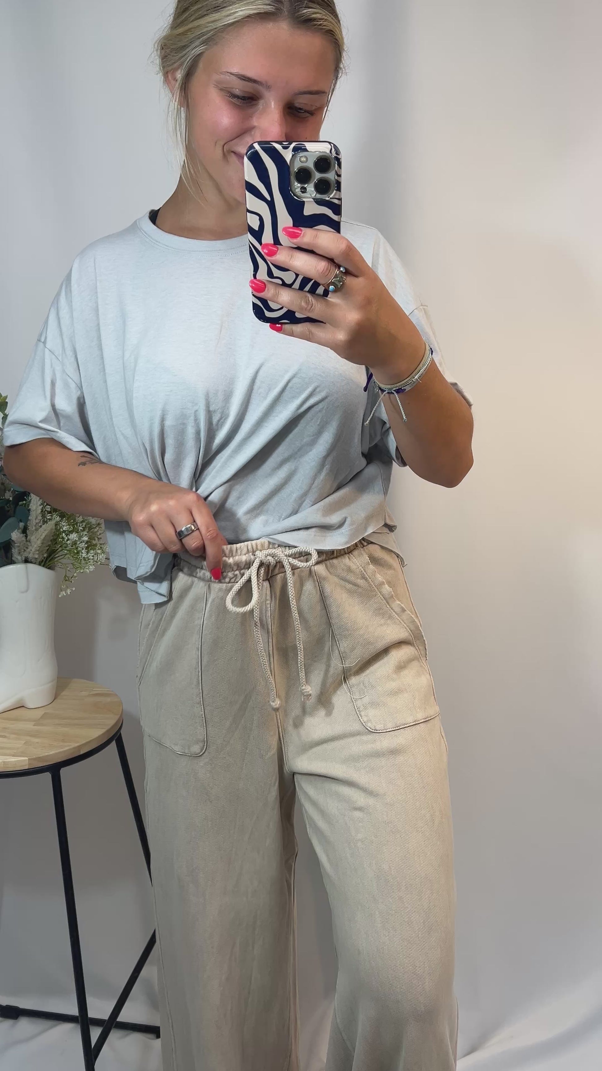 Model showing front and side of beige wide leg lounge pants with adjustable drawstring waist and raw hem for trimming