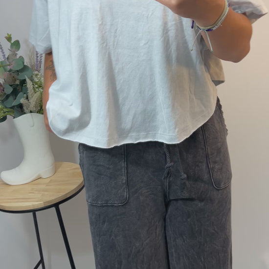 Model turning and walking in charcoal grey lounge pants with flowy wide legs and mineral washed look