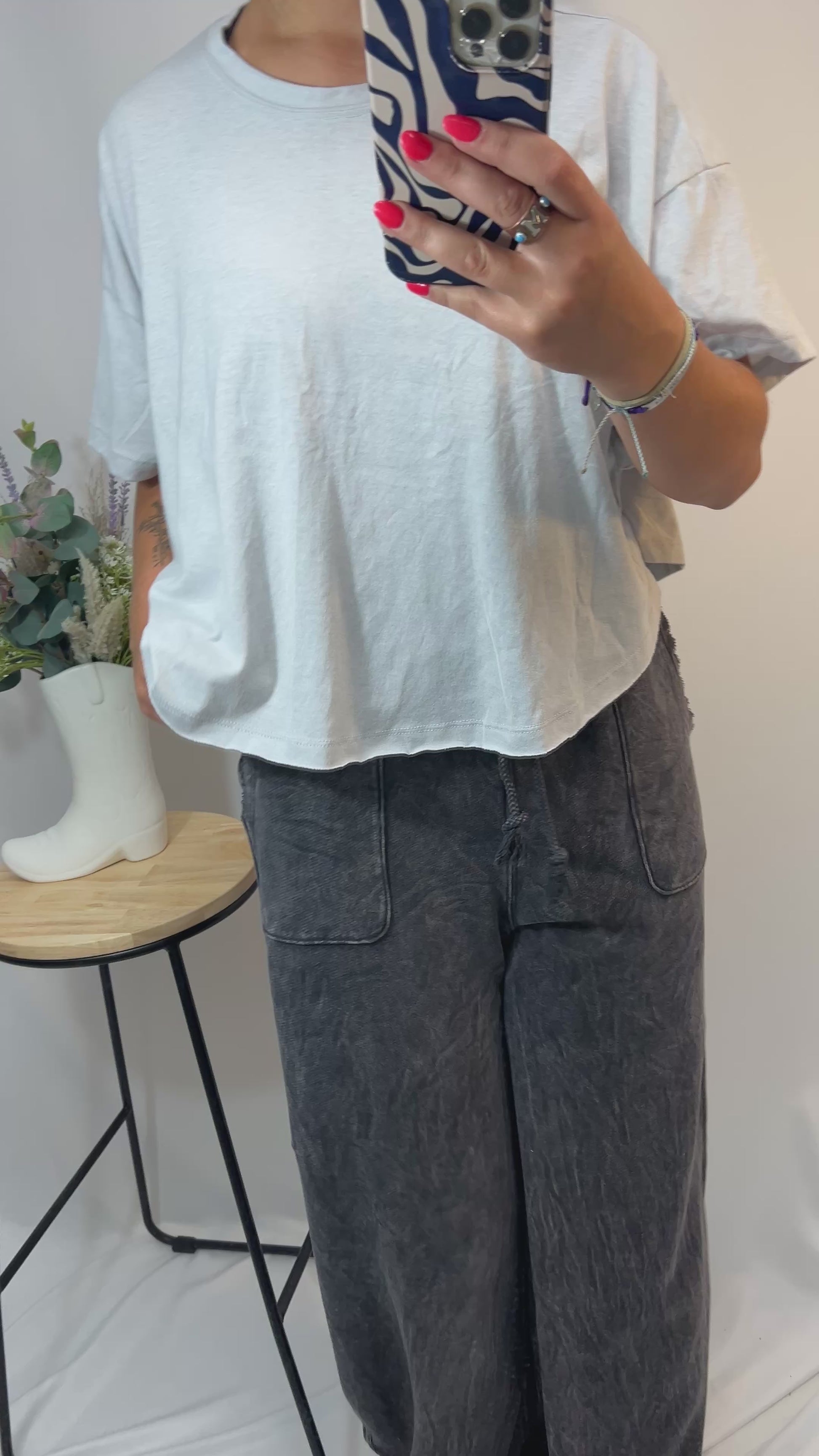 Model turning and walking in charcoal grey lounge pants with flowy wide legs and mineral washed look