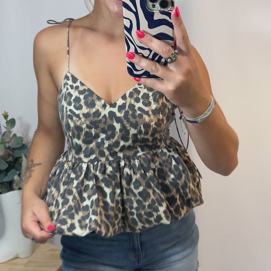 Woman wearing cheetah print bubble hem top with tie straps and denim shorts