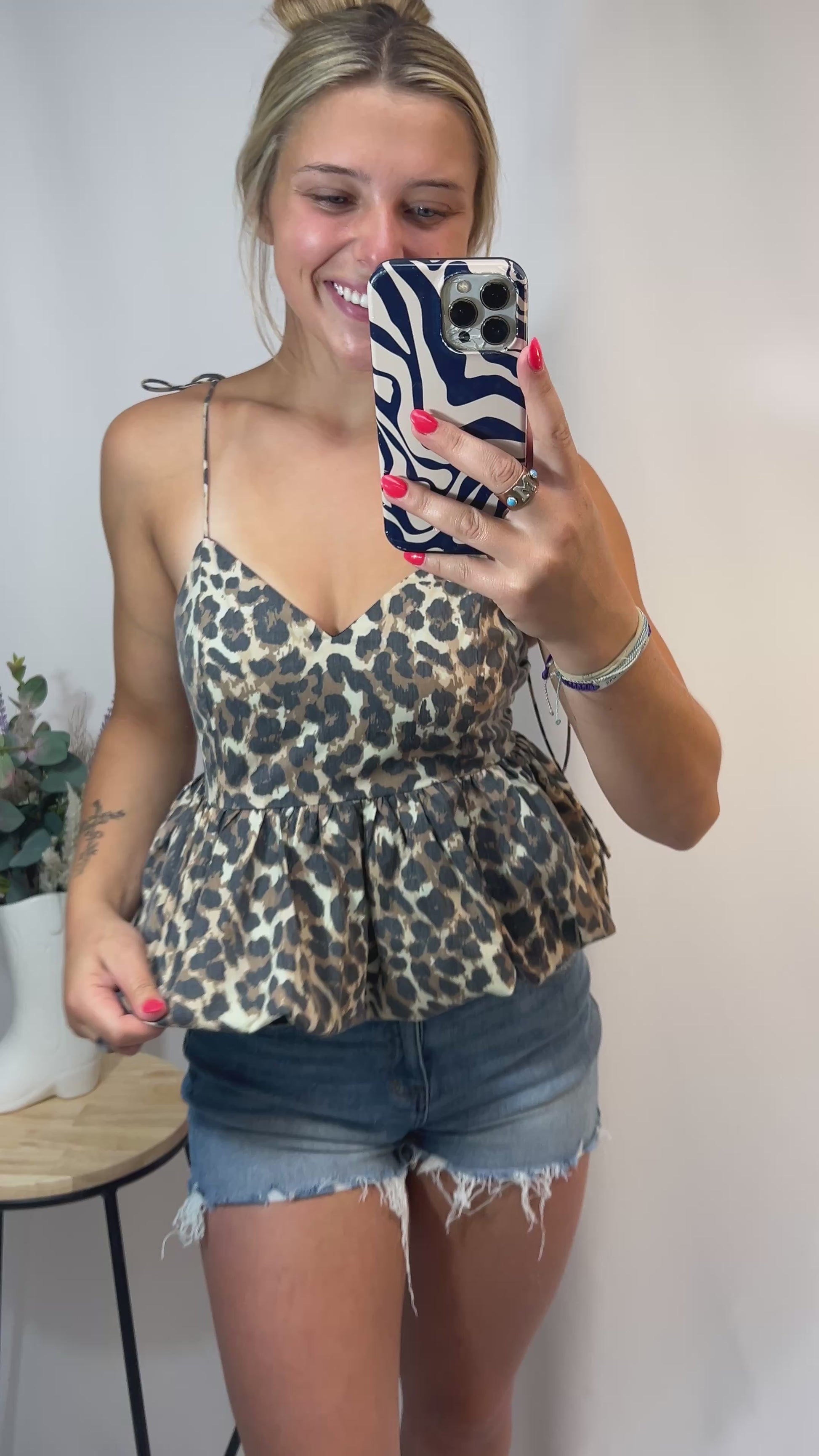 Woman wearing cheetah print bubble hem top with tie straps and denim shorts