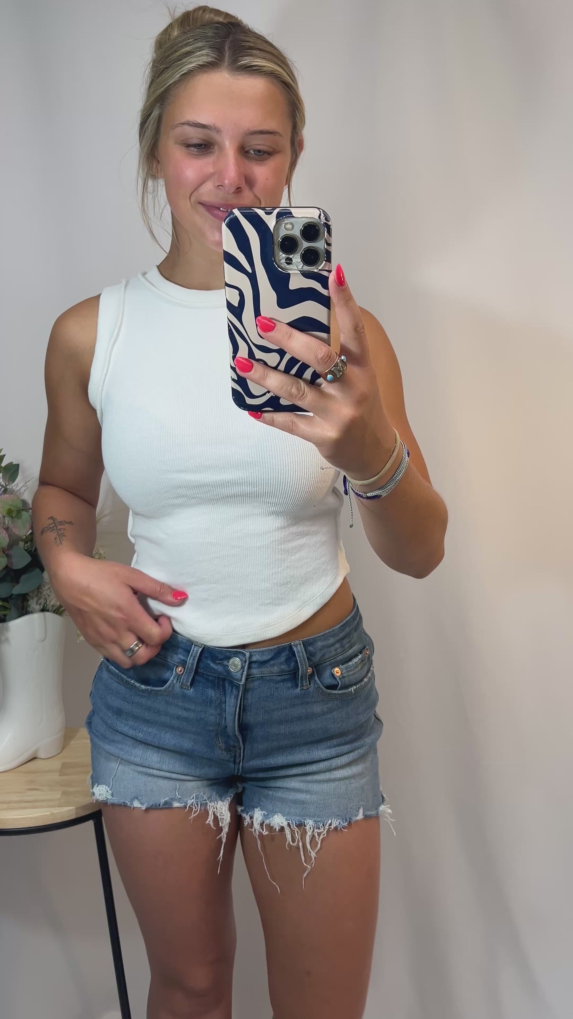360 view of girl modeling white ribbed cotton tank top with high neckline and raw hem, styled for casual streetwear or layering.