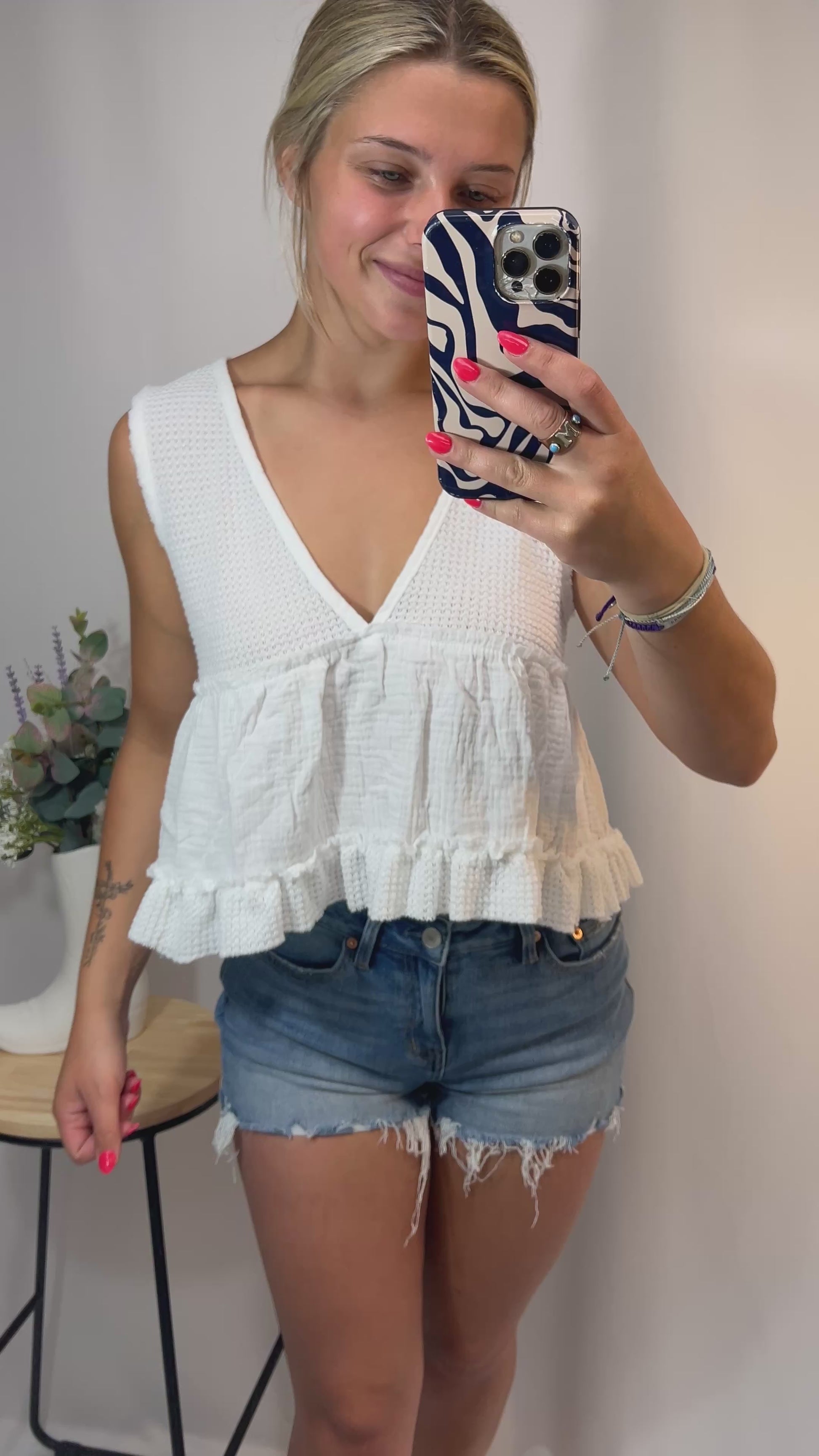 Woman wearing white cropped gauze ruffle top in natural lighting, spinning slightly